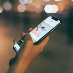 someone holding his smartphone with blurry city lights in the background