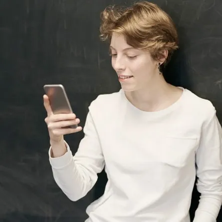 a woman in a white shirt using her smartphone